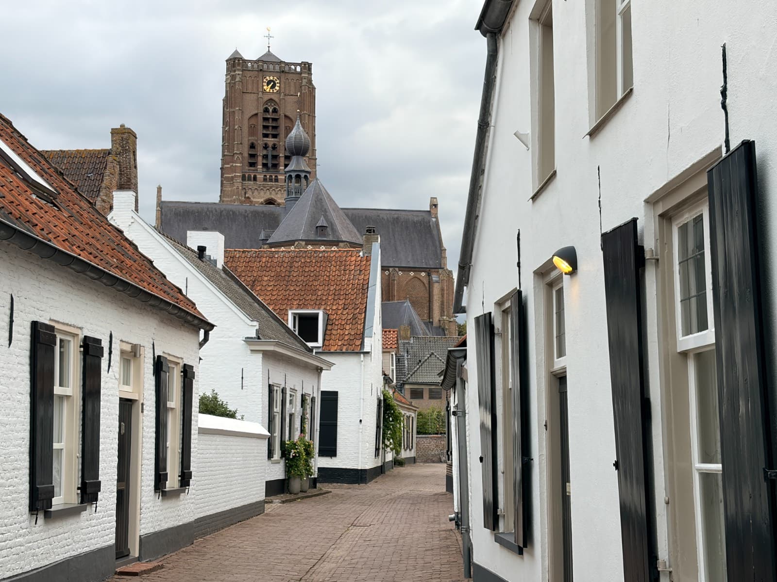 Een smal steegje met witte huisjes en de Sint-Petrusbasiliek erachter
